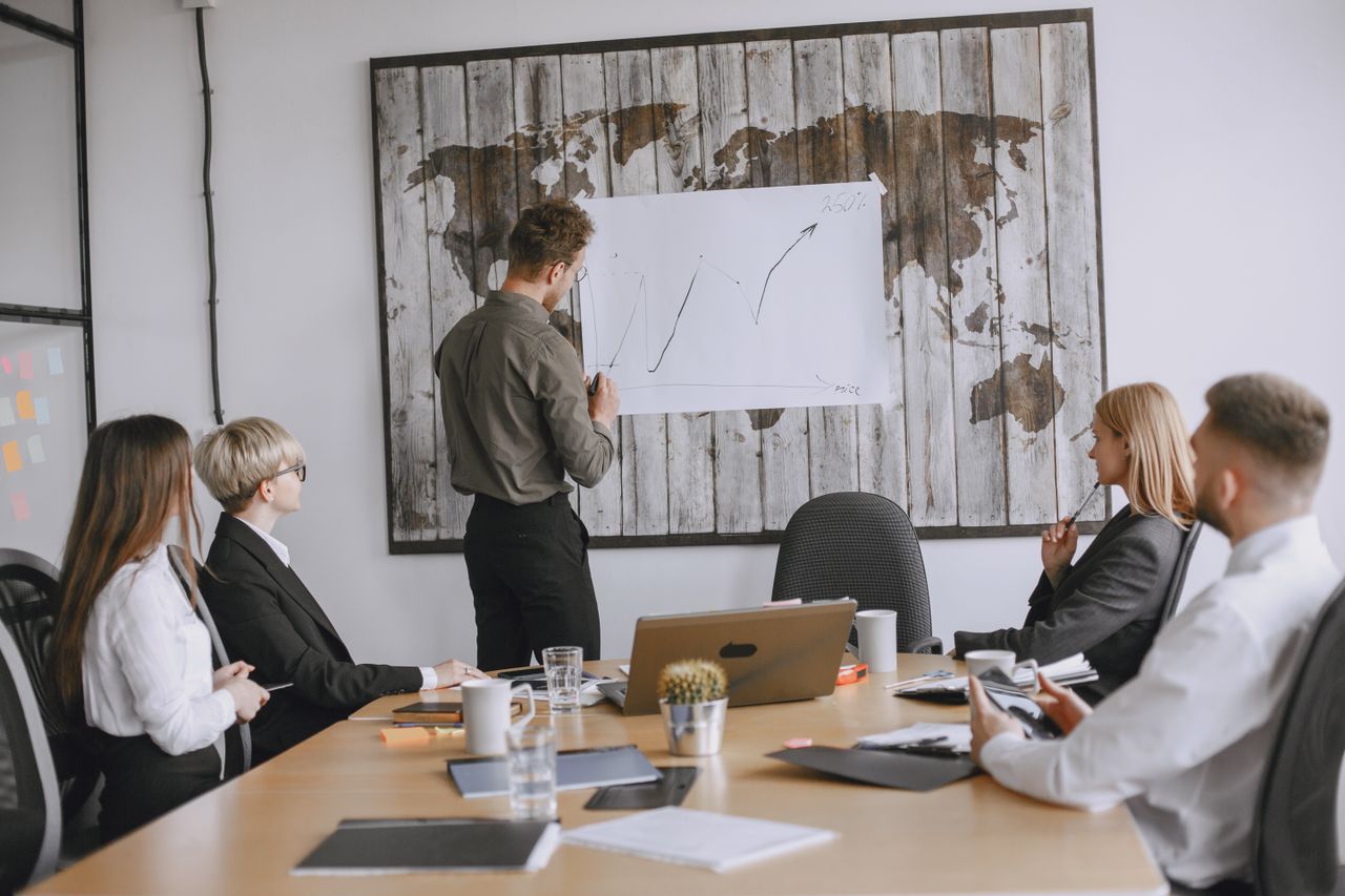 Group of business professionals discussing strategies with growth chart in conference room.