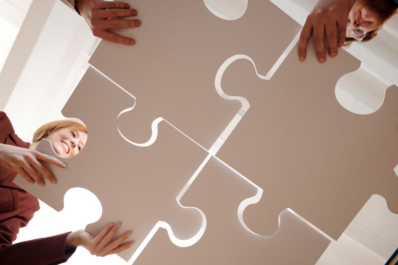 About Low angle view of diverse team assembling large puzzle pieces, symbolizing unity and cooperation.