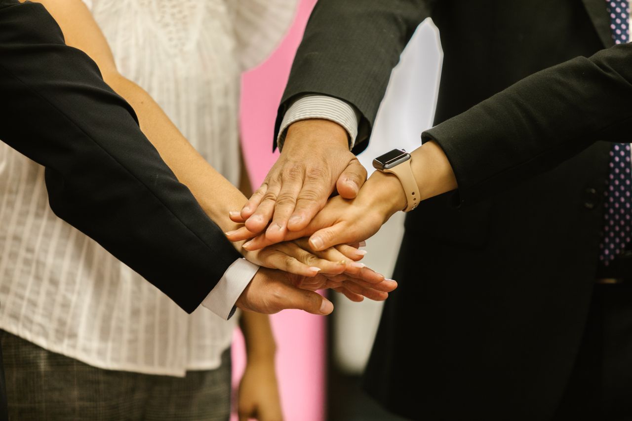 About Close-up of colleagues huddling hands symbolizing teamwork and unity.